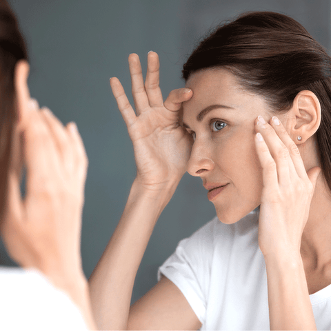 Woman inspecting skin in mirror