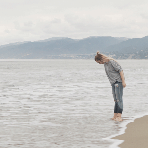 Woman wading in the ocean on cloudy day